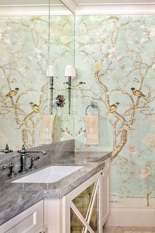 small powder room with wallpaper and mirrored wall, marble countertop, wall lights