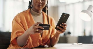 A woman using her credit card to complete an online purchase on her phone.