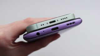Puhelimen latausportin puhdistus: Lightning- ja USB-C-latausliitännällä varustetut puhelimet vierekkäin ihmisen kädessä
