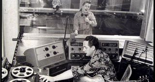 Les Paul and Mary Ford in the studio, with Paul in the control room holding an early version of his Gibson signature model, with Ford checking in between vocal takes.