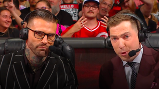 Corey Graves and Kevin Patrick speak at the commentary desk during an episode of WWE Monday Night Raw.