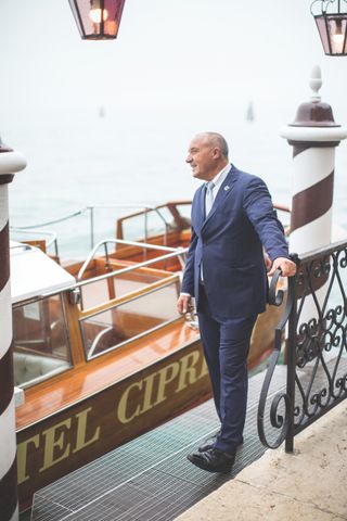 Man in a blue suit standing next to a private Venetian water taxi