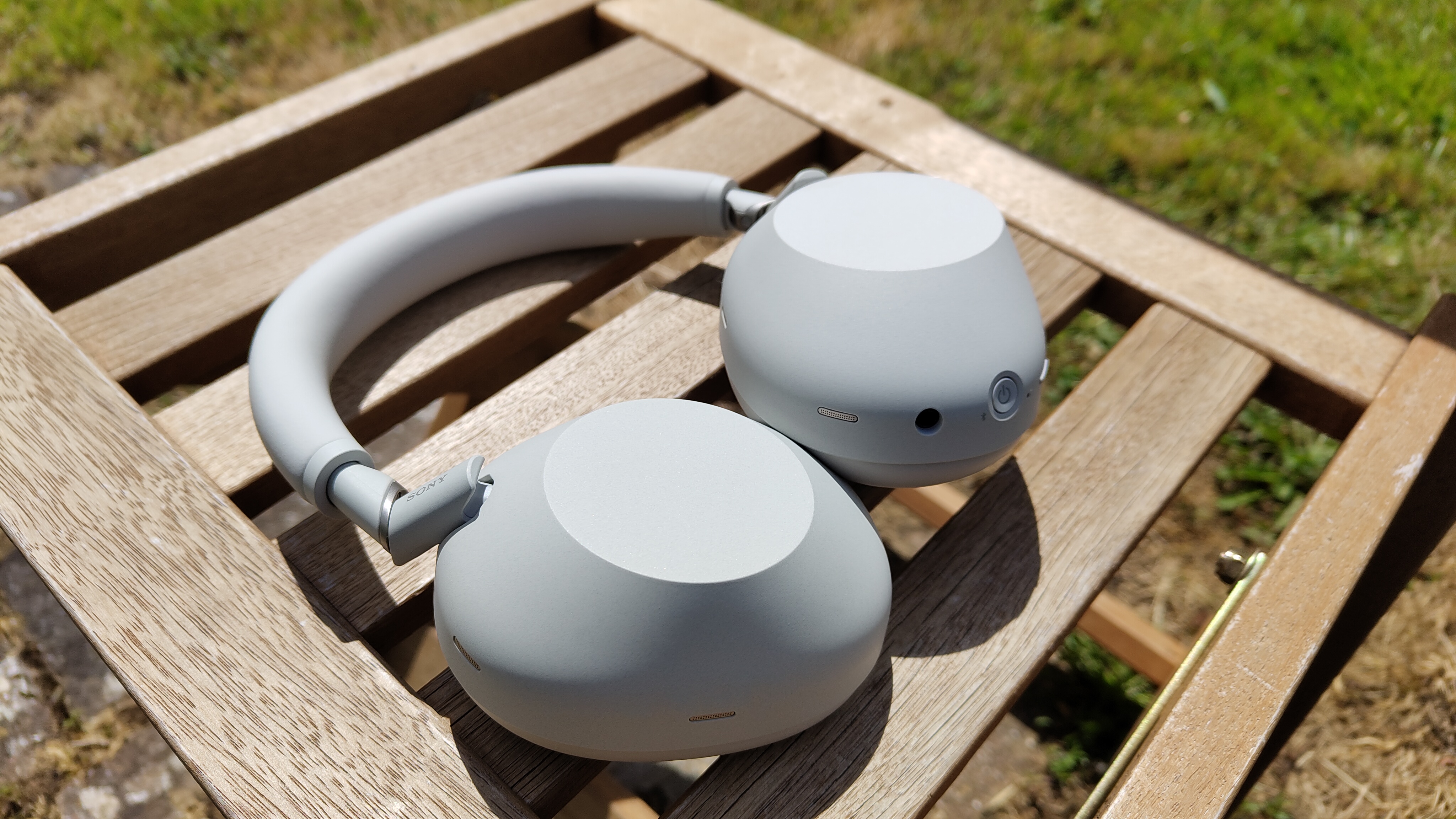 Sony WH-1000XM6 in white on an outdoor wooden chair