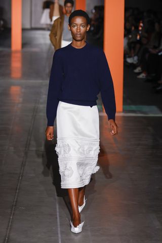 Woman on Prada runway i white skirt embellished with flowers