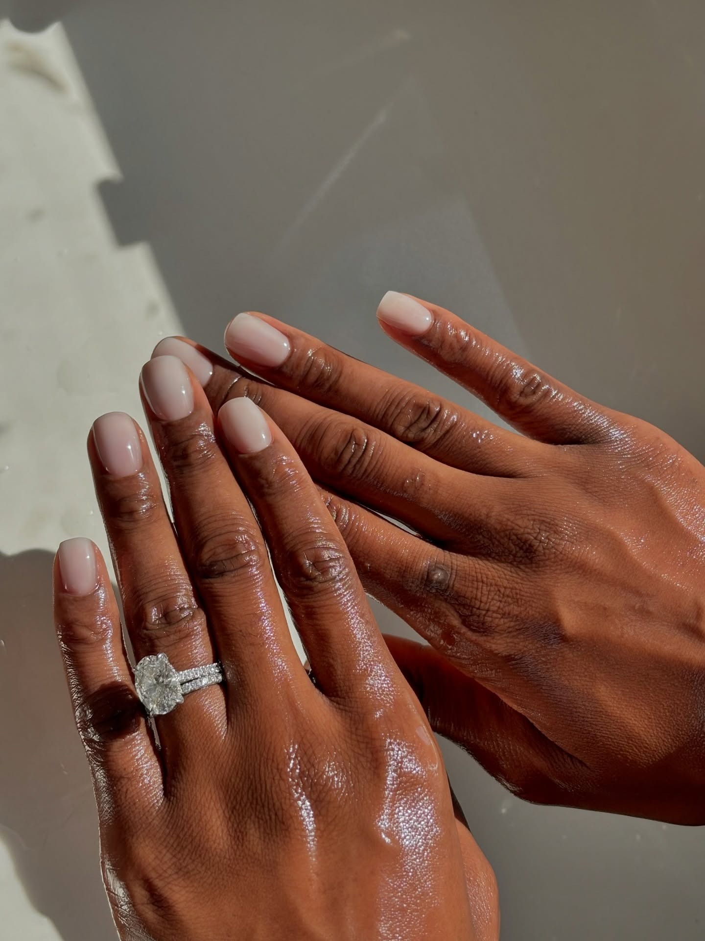 Hands with short nails with a sheer pink nail colour