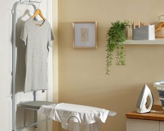 Pale yellow small laundry room with fold-out ironing board