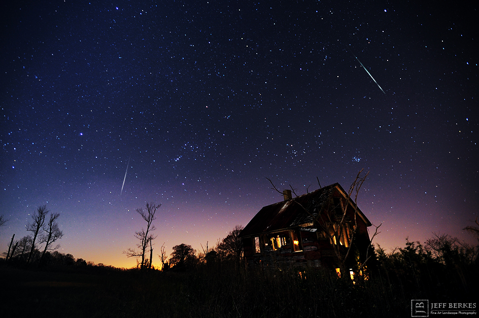 fireballs streak through a starry sky above a cabin