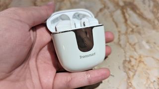 Tronsmart Onyx Ace Pro wireless earbuds inside case with lid open, held in one hand