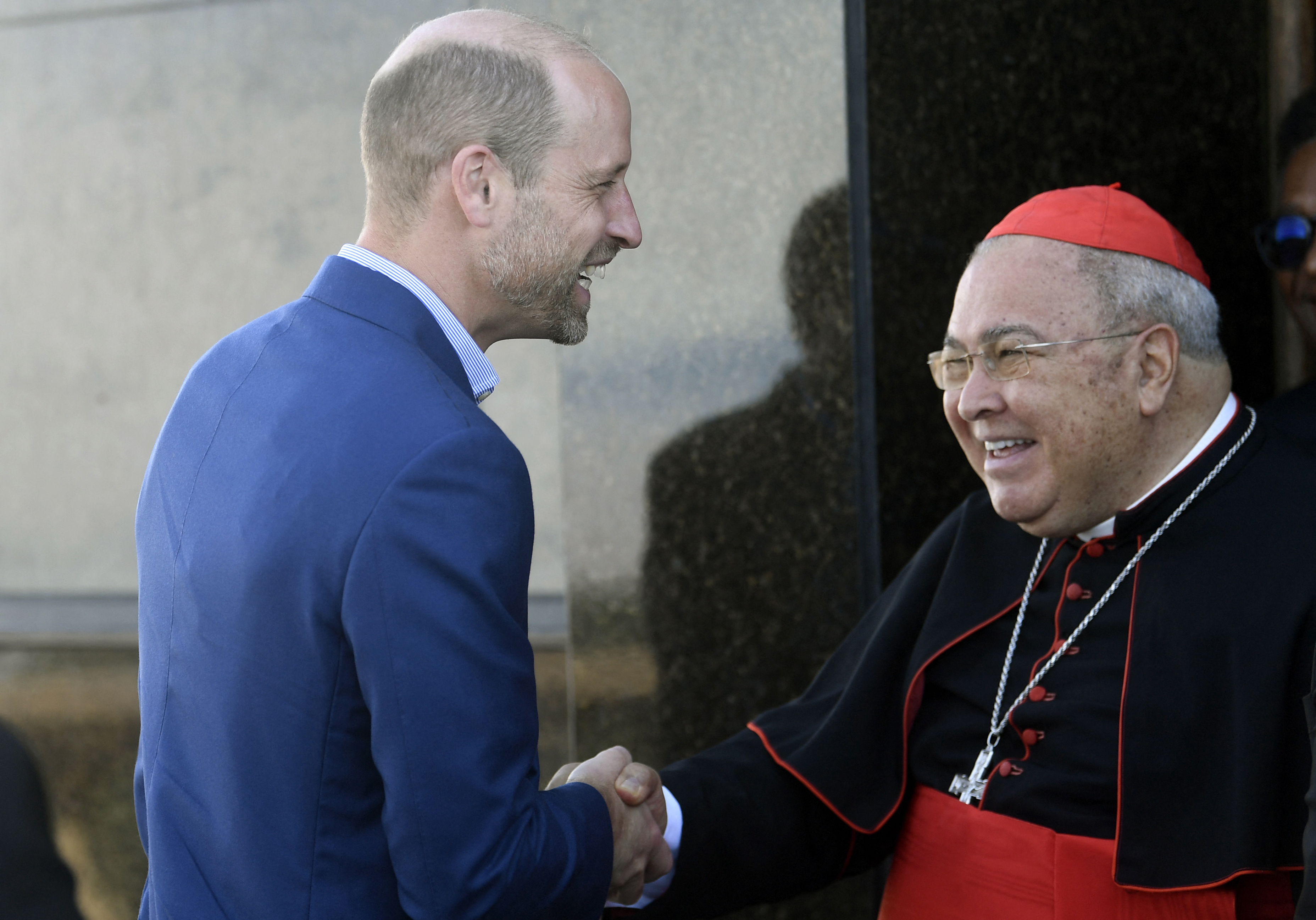 Prince William wearing a blue blazer shaking hands with Rio de Janeiro Archbishop Orani Tempesta at the Christ Redeemer Sanctuary in Rio de Janeiro, Brazil