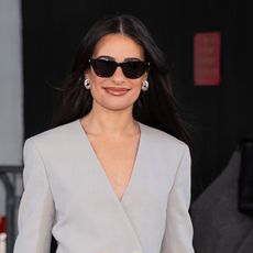 Lea Michele wears sunglasses and a gray blazer.