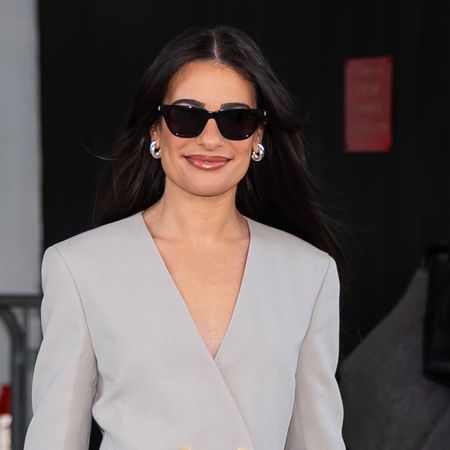Lea Michele wears sunglasses and a gray blazer.