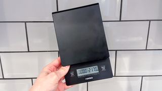 a black coffee scale by Hario is photographed in real-life usage in a kitchen