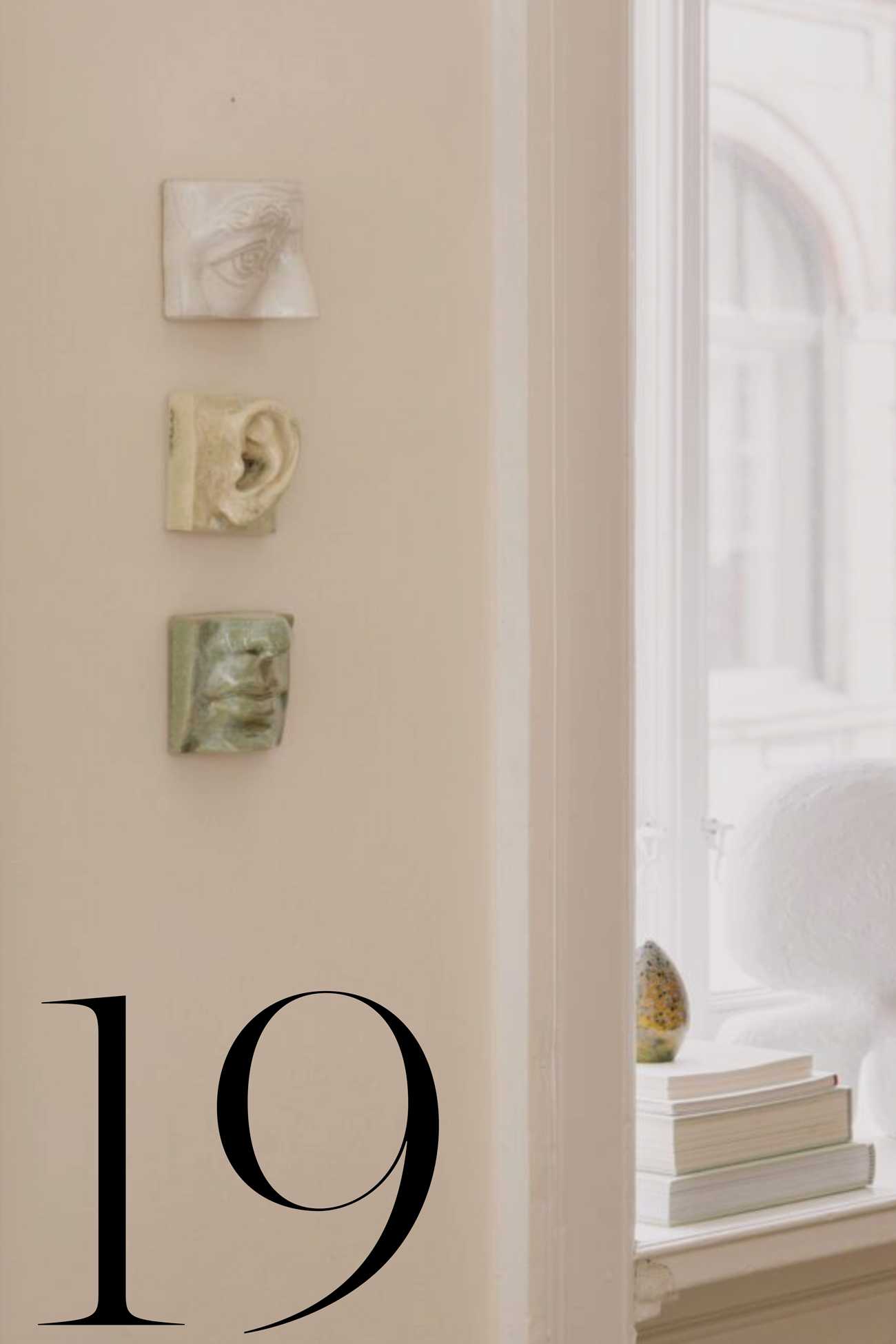 white room with windowsill styled with books, and three ceramic wall decor hanging on the wall