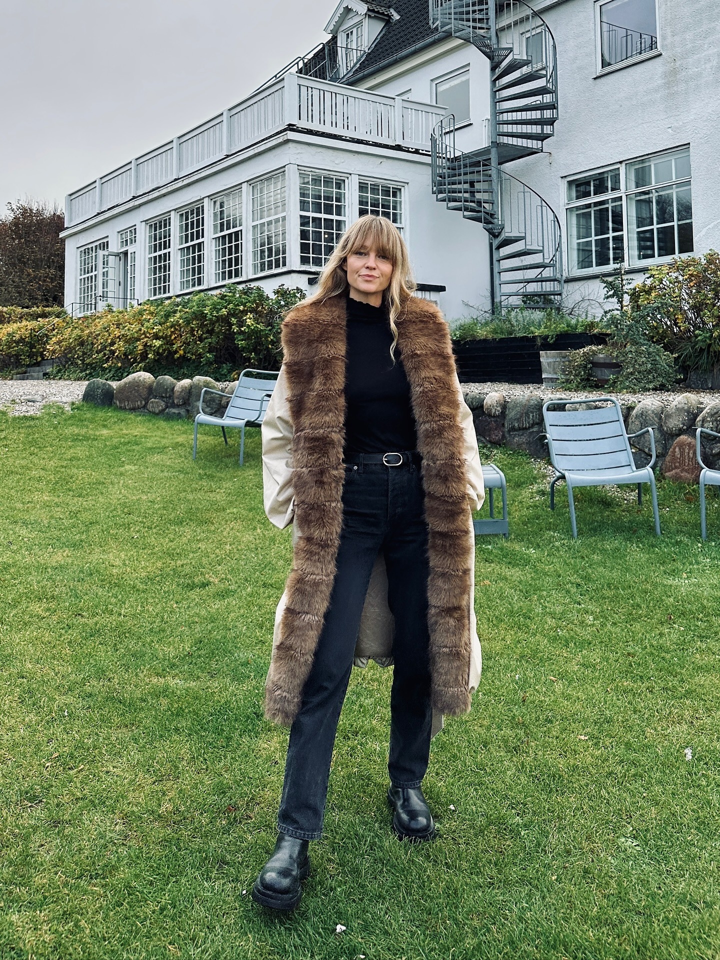 Woman wearing black jeans, black shirt, and fur-trimmed coat.