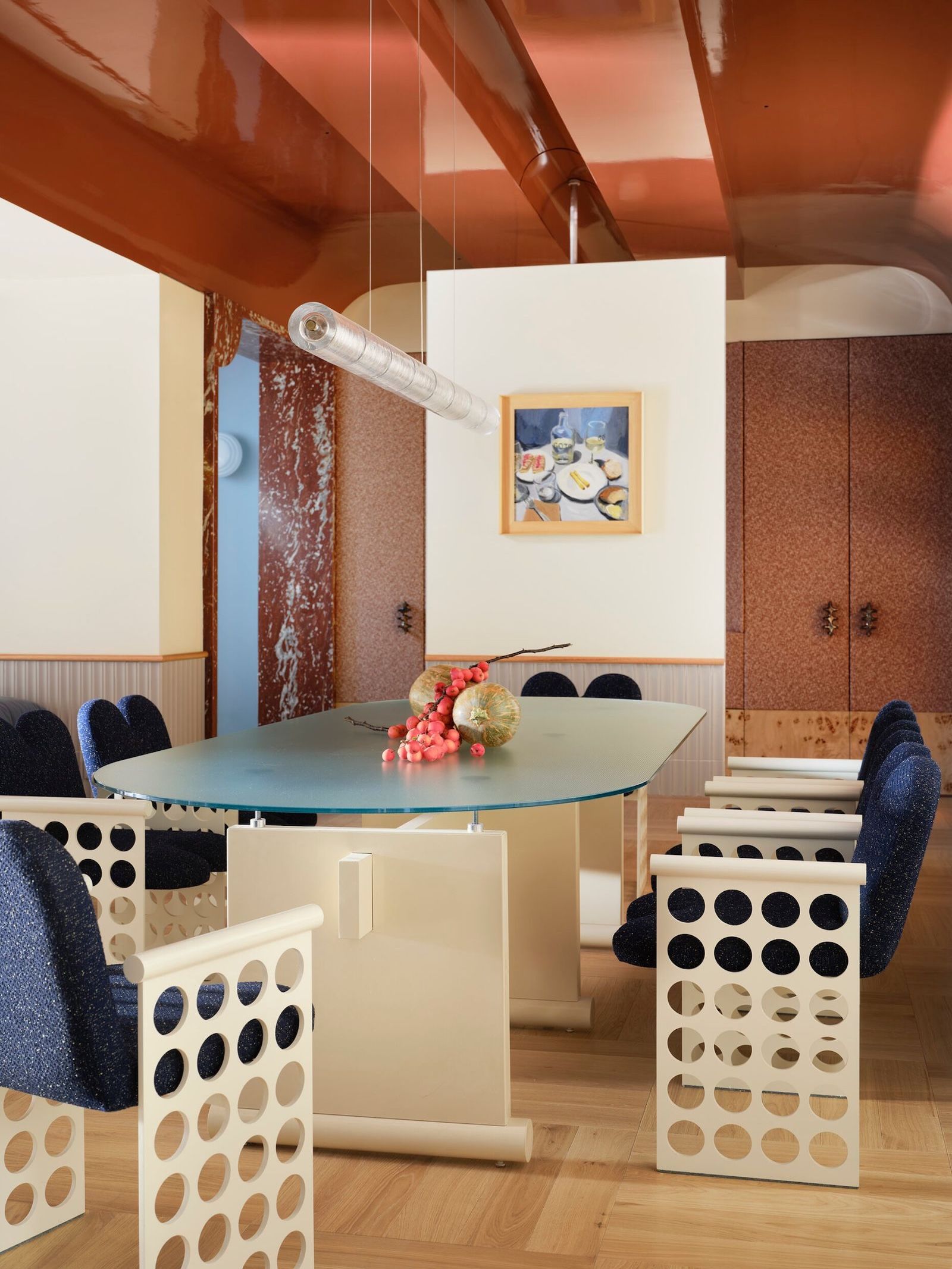 A contemporary dining room with terracotta marble, orange upholstered doors in the background, and a gloss ceiling in complementary tones