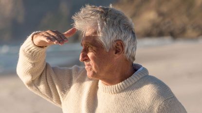 Senior man at the beach shielding his eyes from the sun
