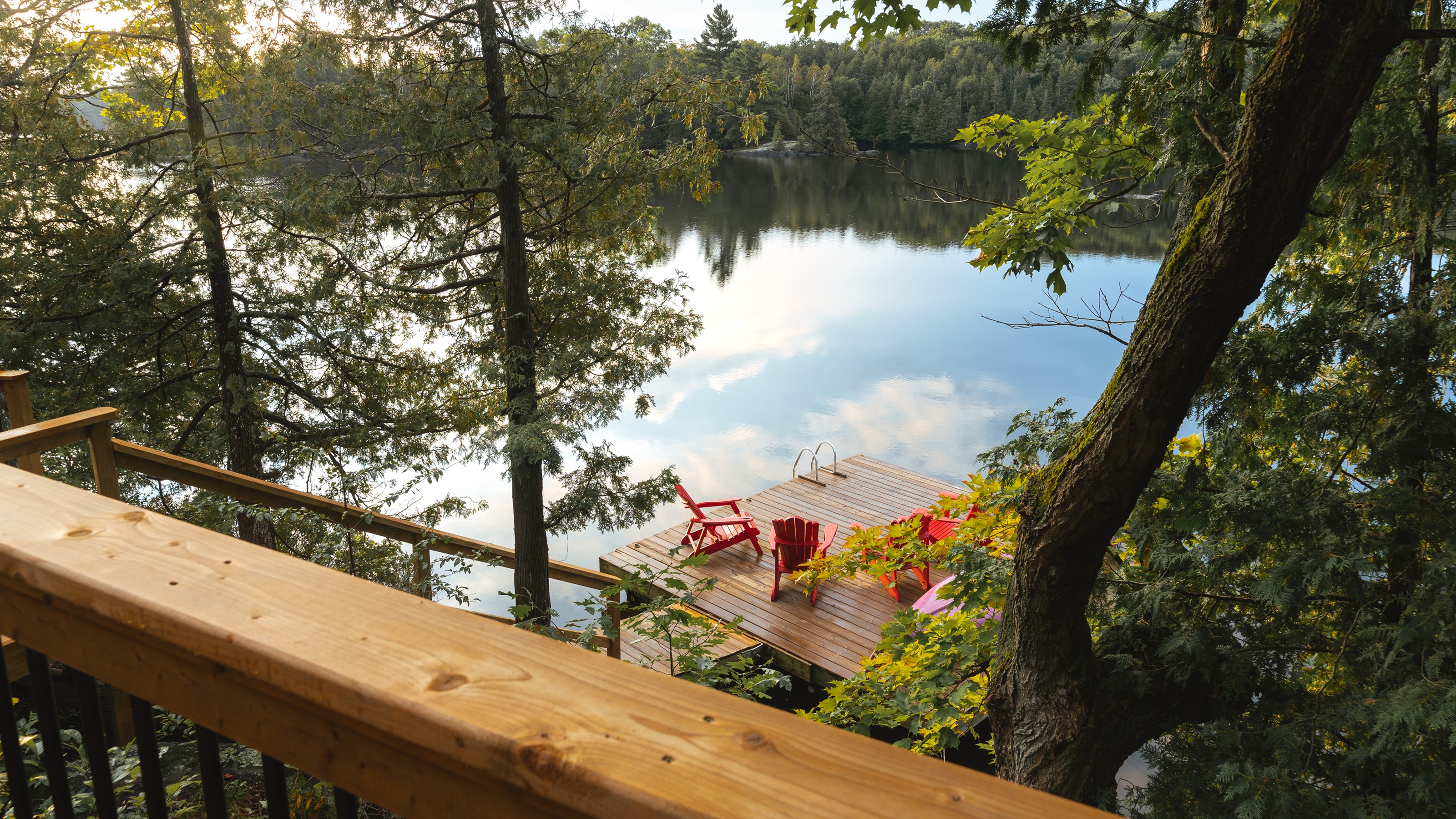The view of a dock and the lake from the balcony of a lakeside home.