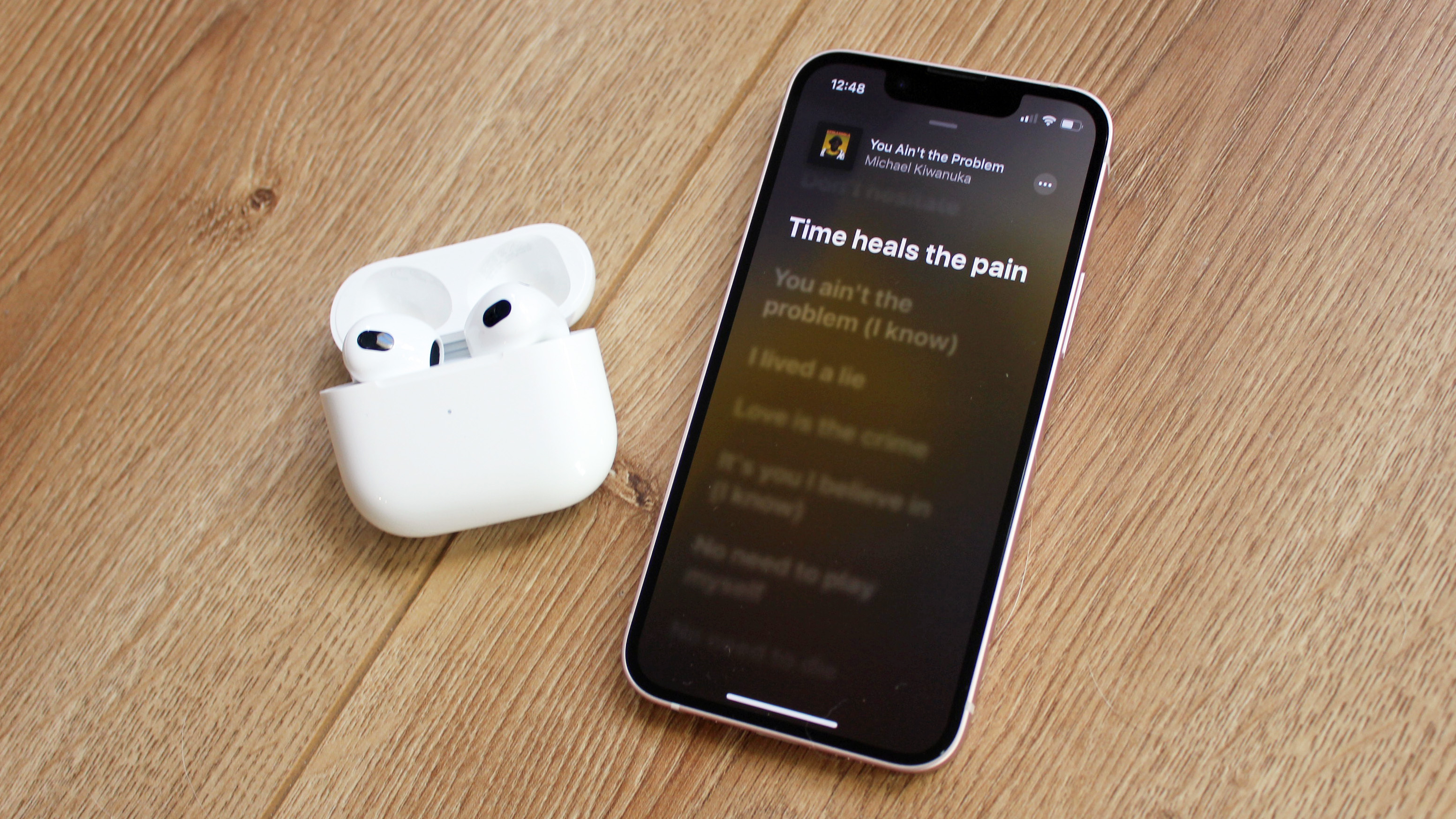 the airpods 3 next to an iphone playing apple music