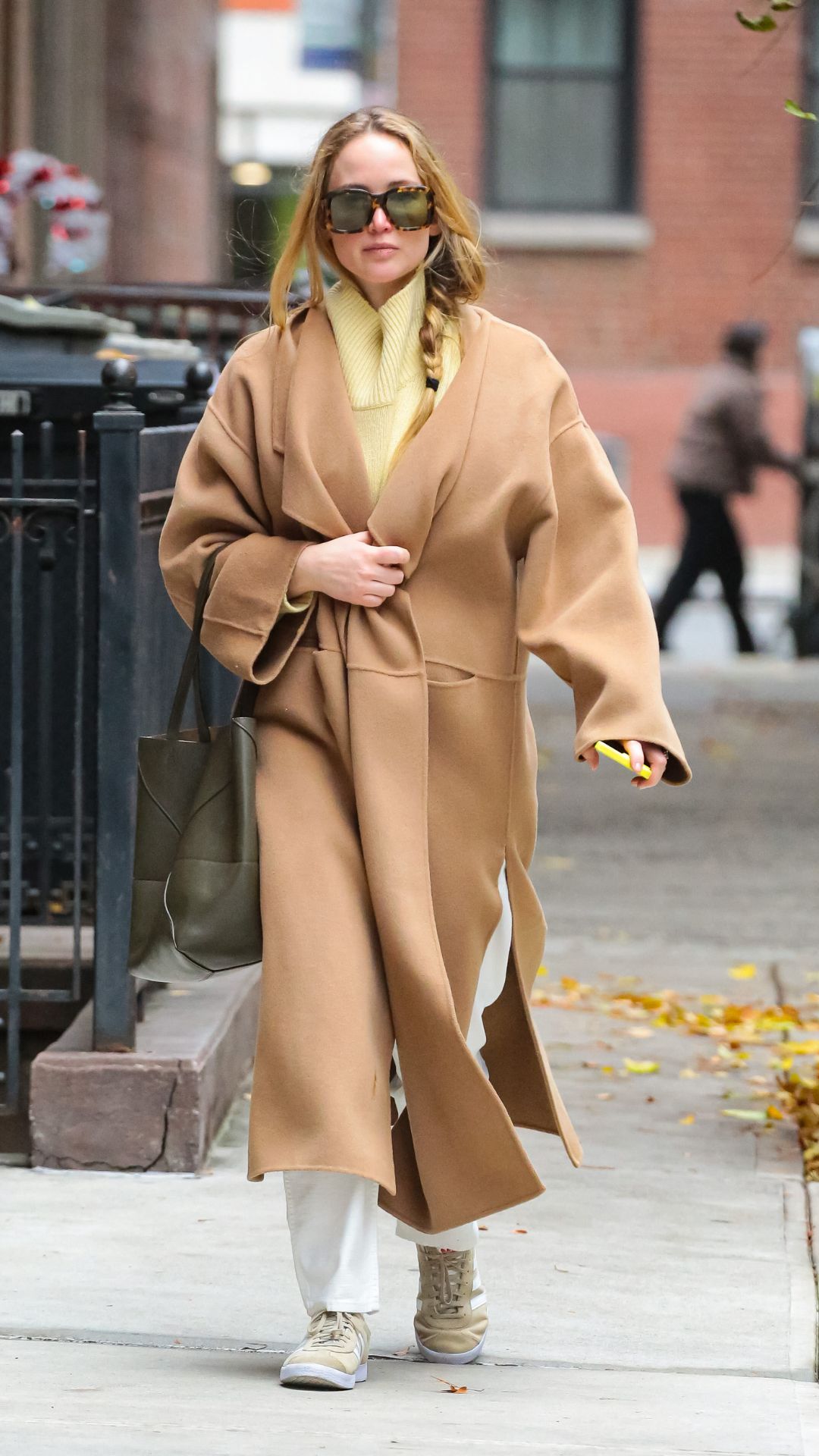 jennifer lawrence wearing a camel coat and trainer outfit