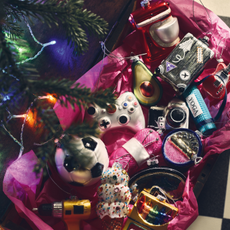 Box with pink tissue paper holding M&S's hobby-themed baubles. There is a stand mixer, avocado, camera, football, drill and yoga mat