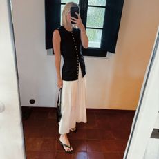 Natalie Cantell taking a mirror selfie in Menorca, wearing a white skirt and leather flip flops from Mango, and carrying bag from Celine