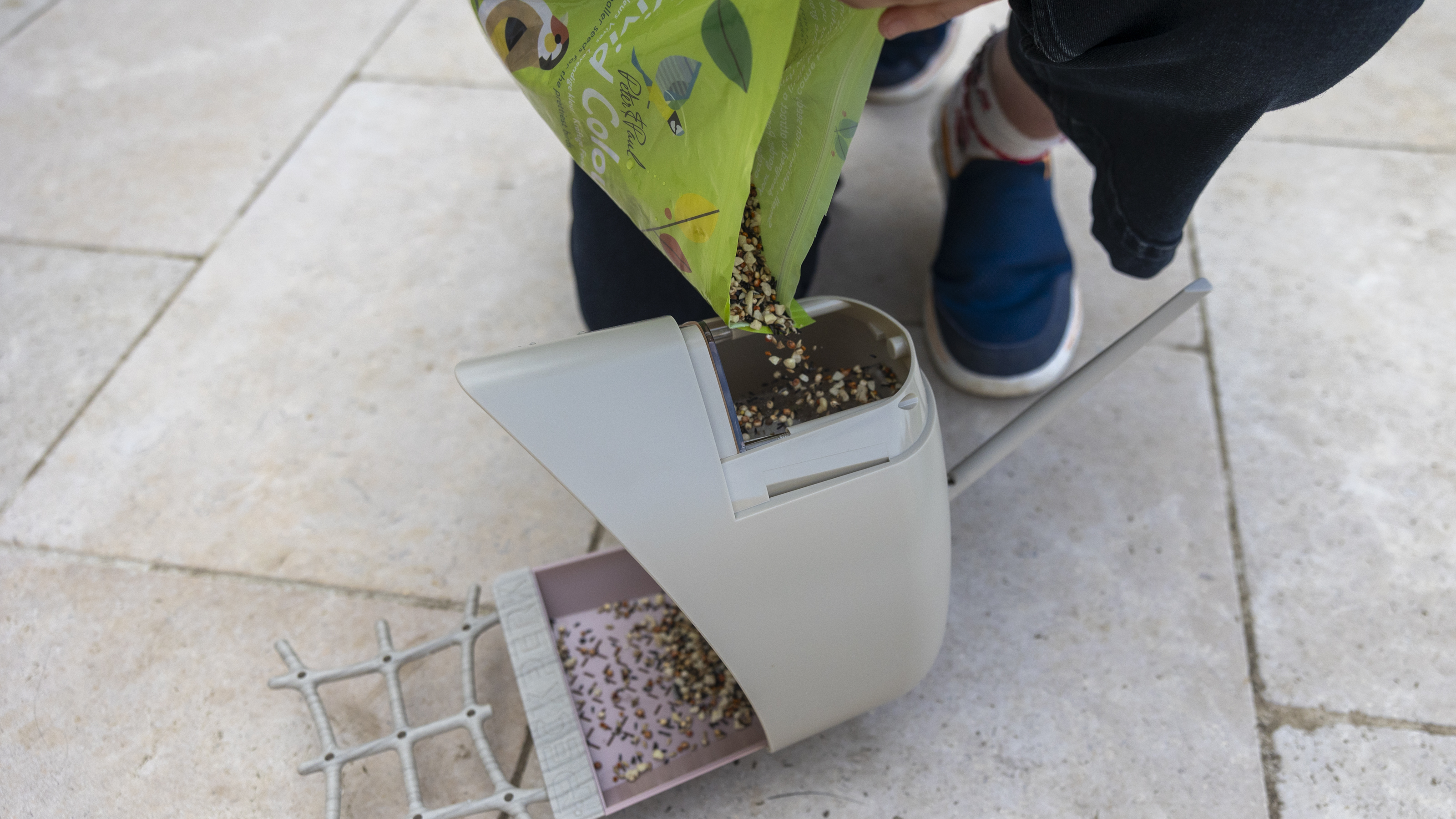 A woman filling up the PeckPerk bird feeder camera with seed