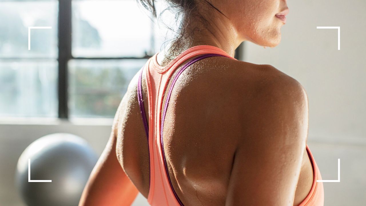 Woman with her back to the camera, wearing bright purple sports bra after learning how to wear a sports bra