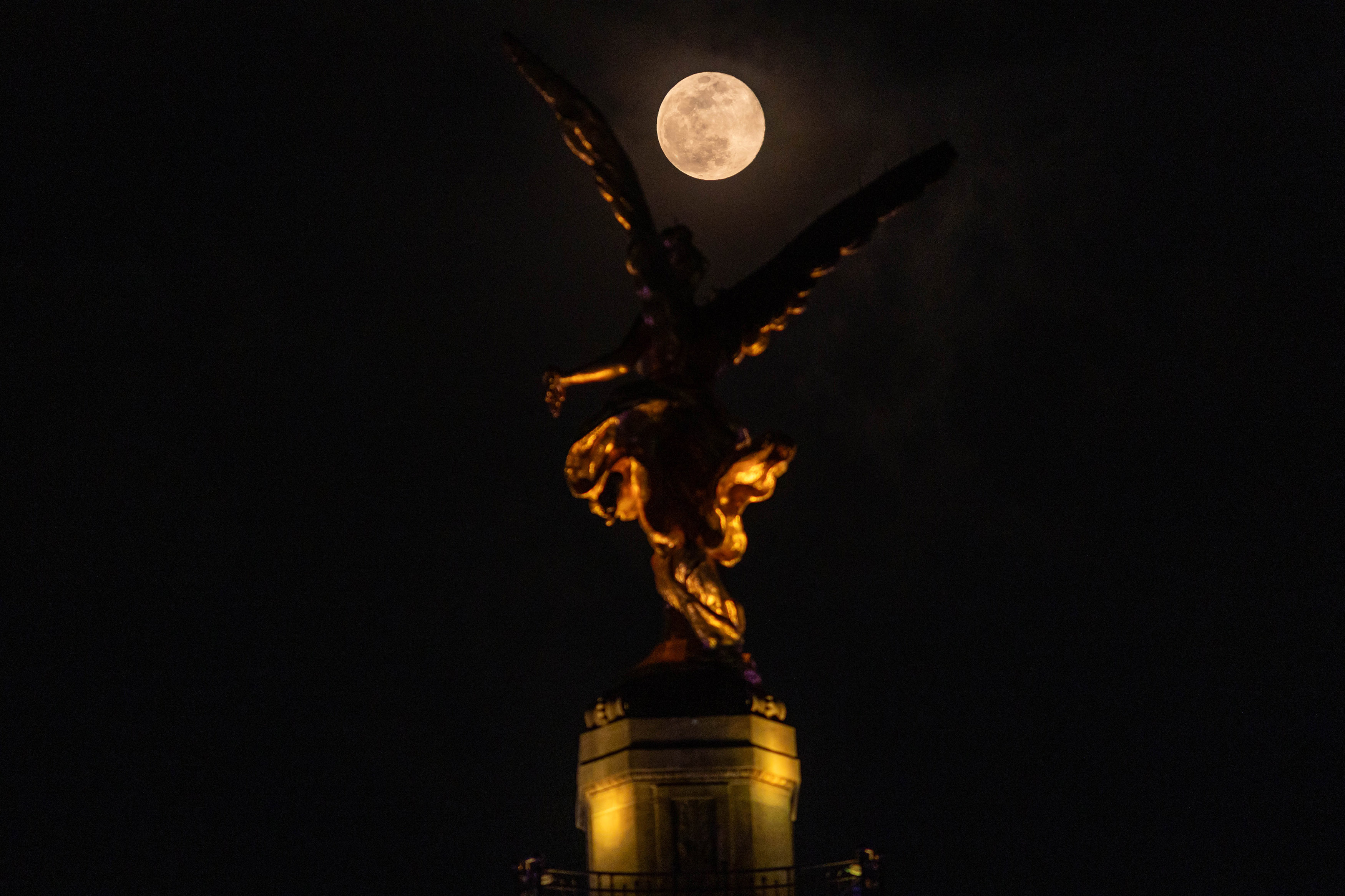 A photo of the supermoon rising over the Angel of Independence monument in Mexico City, Mexico.
