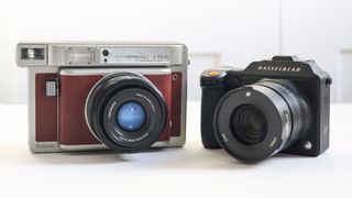 The Lomo'Instant Wide Glass side by side with a Hasselblad X2D 100C, on a white surface against a white background