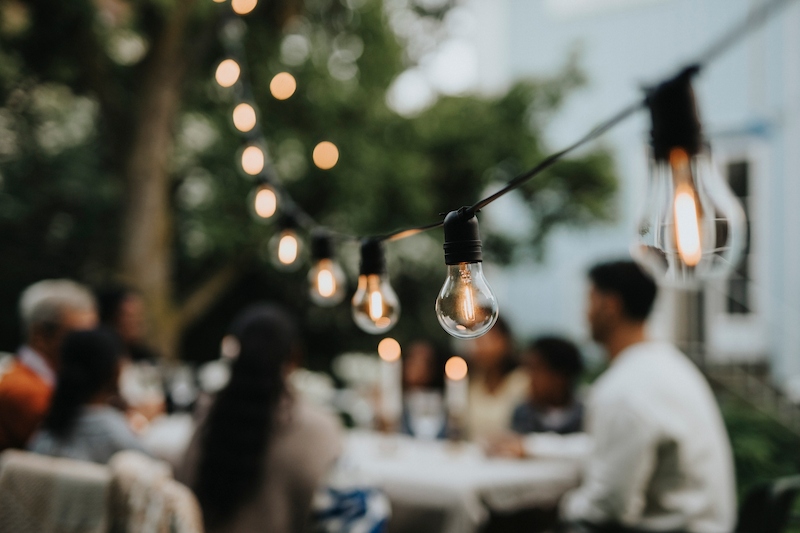 Illuminated string lights hanging in garden during party.