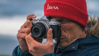 Nikon Z fc being used by a man with a red beanie hat