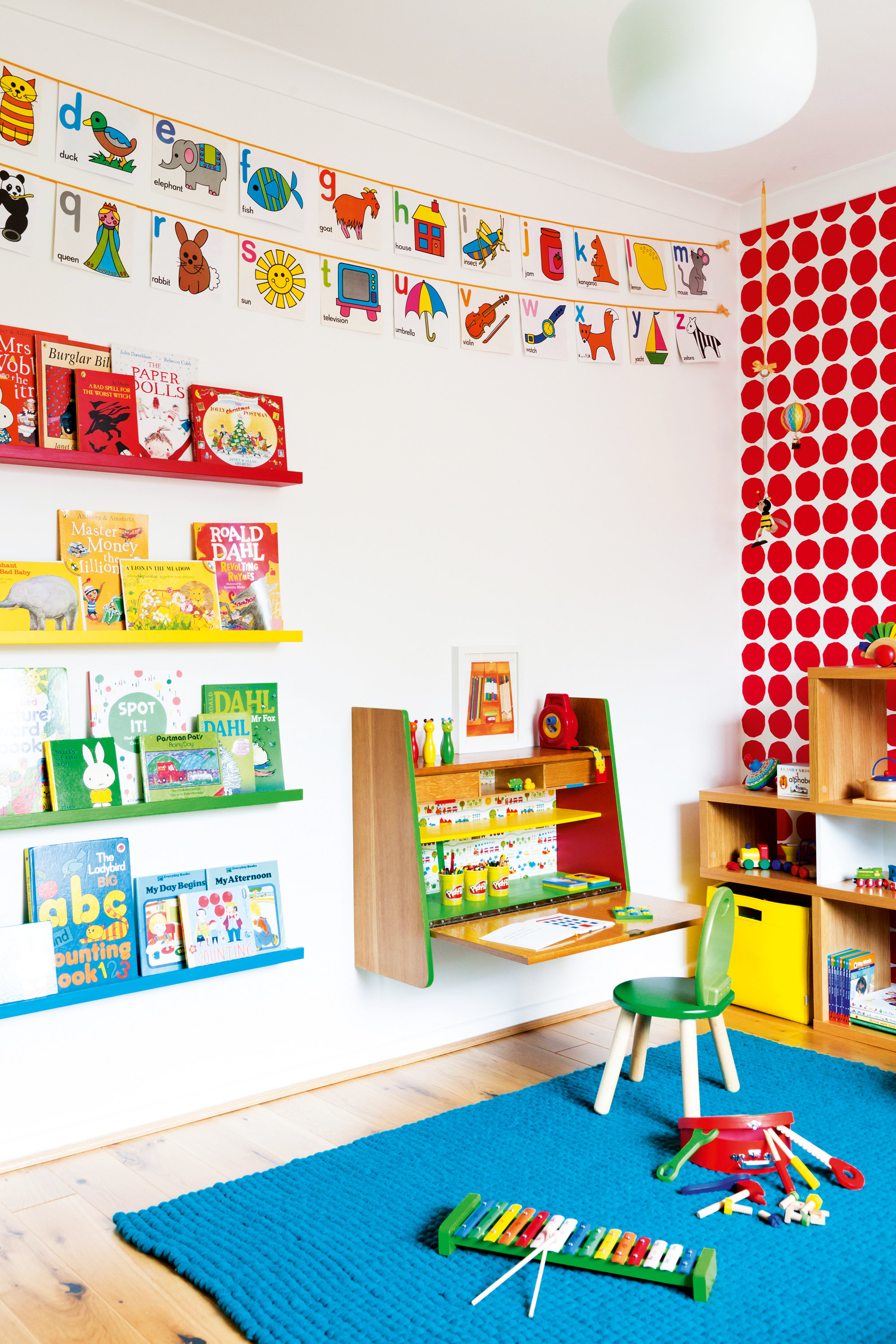 Child's room with red spotty wallpaper and a wall-hung desk