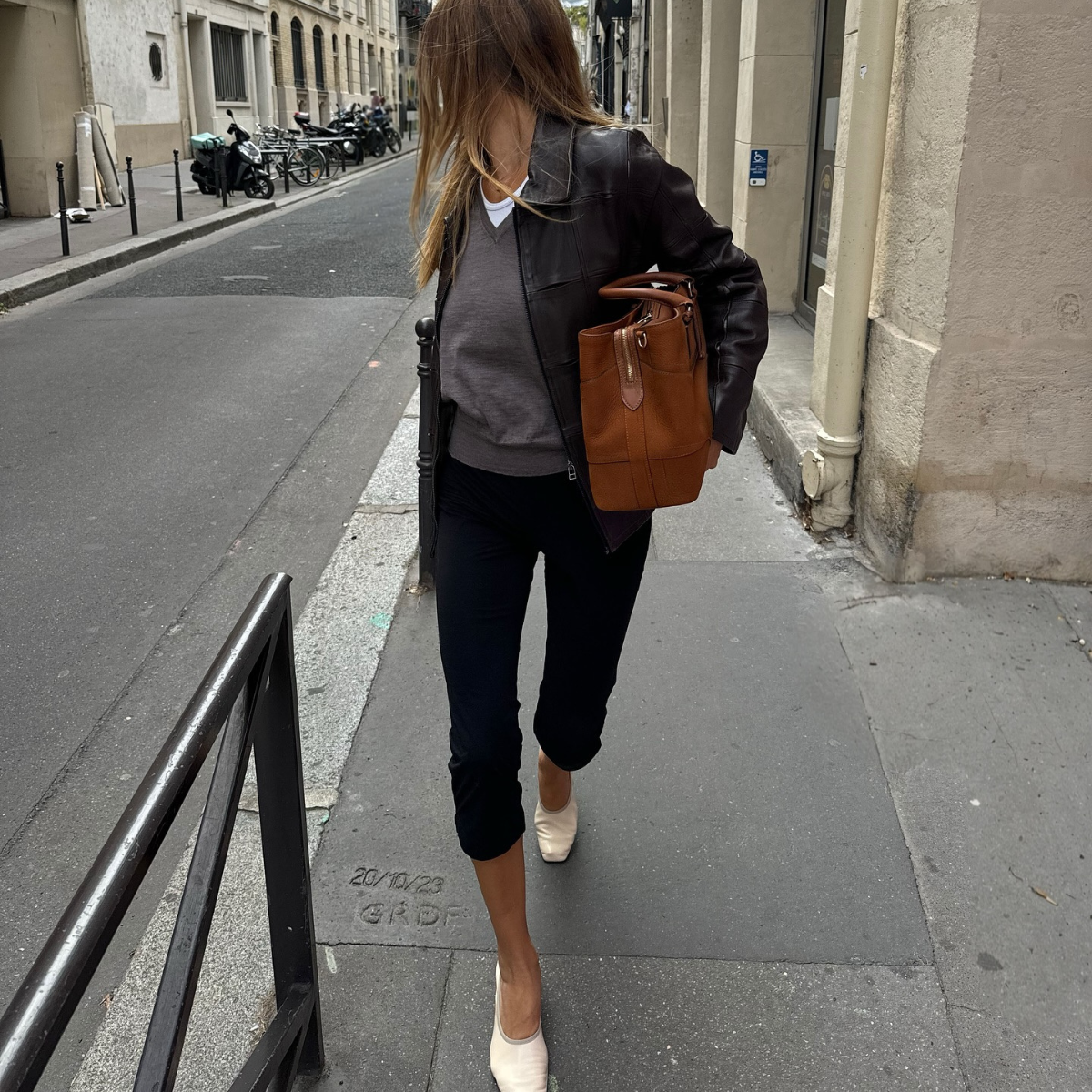 Fashion person annelauremais wears a leggings outfit 2026 . She wears black capri leggings, a grey jumper, white t-shirt and washed black leather jacket. She carried a brown bag in a recent image taken from her Instagram.