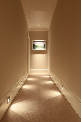 Corridor style landing with neutral decor with skirting board lighting creating pattern on floor