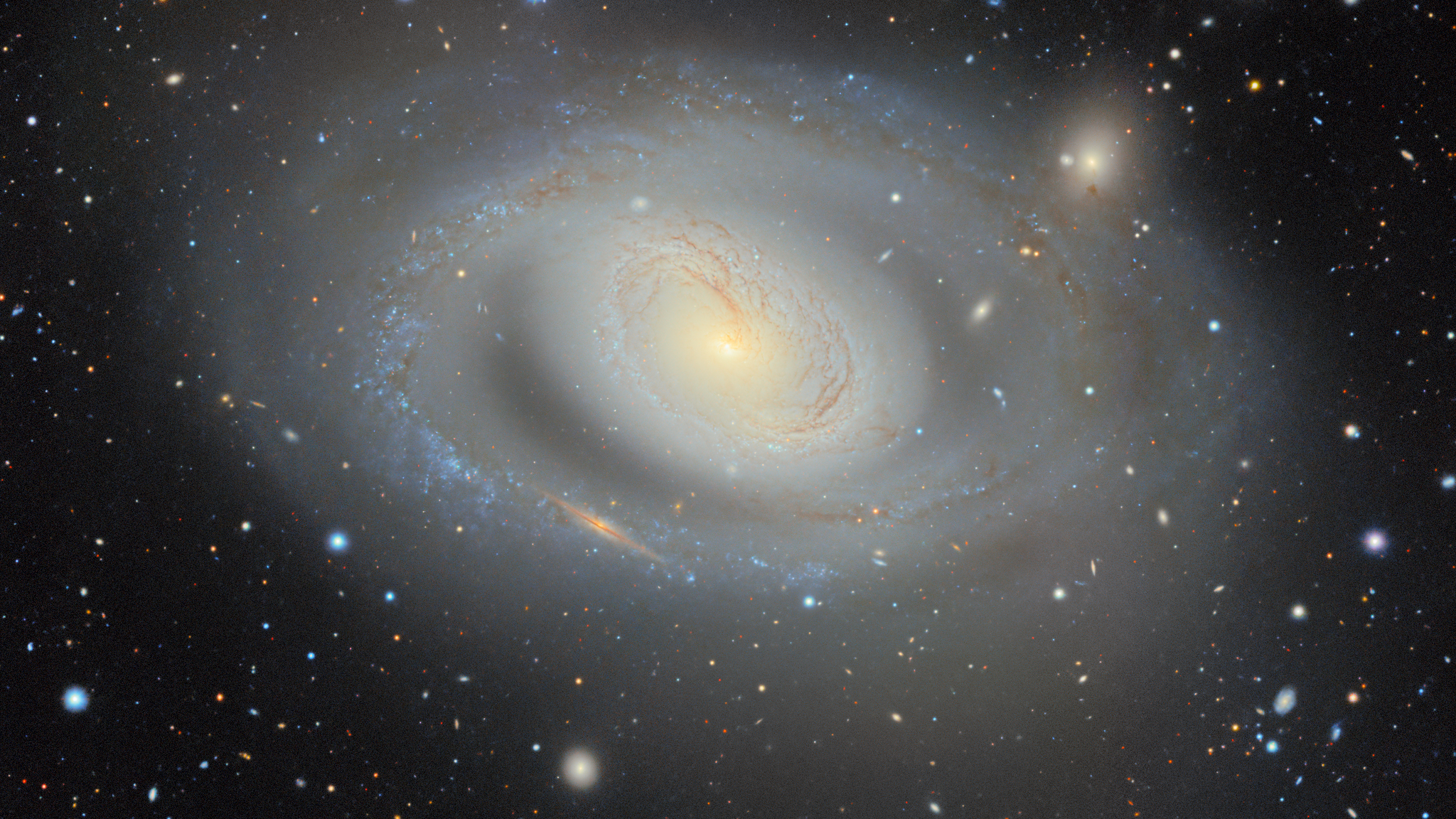 A spiral galaxy glows white in the darkness of space