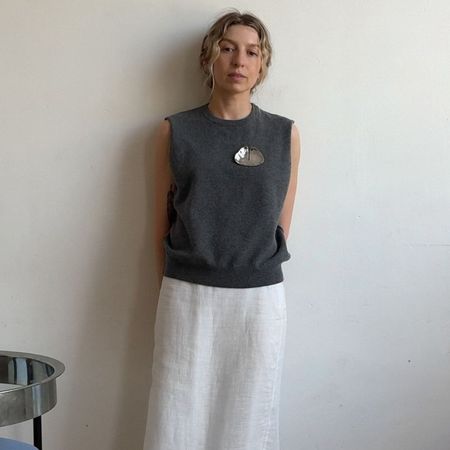 Influencer @brittanybathgate wears a silver brooch with a grey sleeveless knit, a white linen skirt and soft ballet flats.