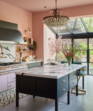 Kitchen with crittall doors, chandelier, black island and pink walls