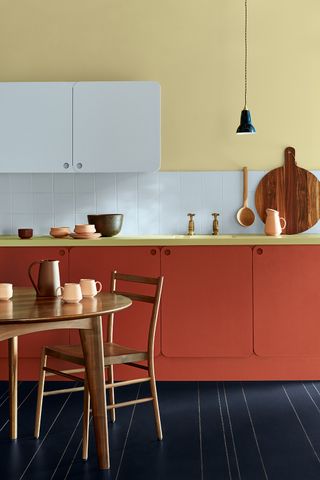 Red kitchen cabinets with wooden worktop and wooden kitchen accessories and a mid-century dining table and chairs