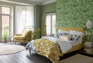 Botanical wallpaper in a bedroom with a yellow bed and chair