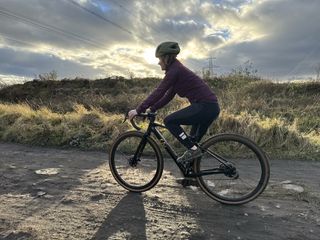 The author, Immy Sykes, riding the Liv wearing a purple endura jacket and tights on a muddy gravel trail