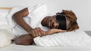 Man in bed wearing sleep mask