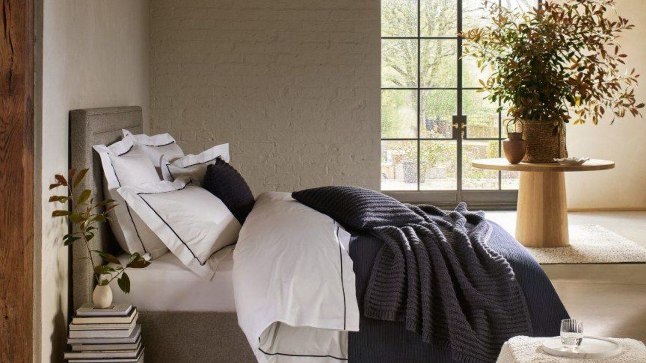 Bedroom with large window and table with vase of folliage