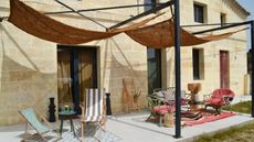 a woven coconut fibre sun shade over a relaxed outdoor seating area