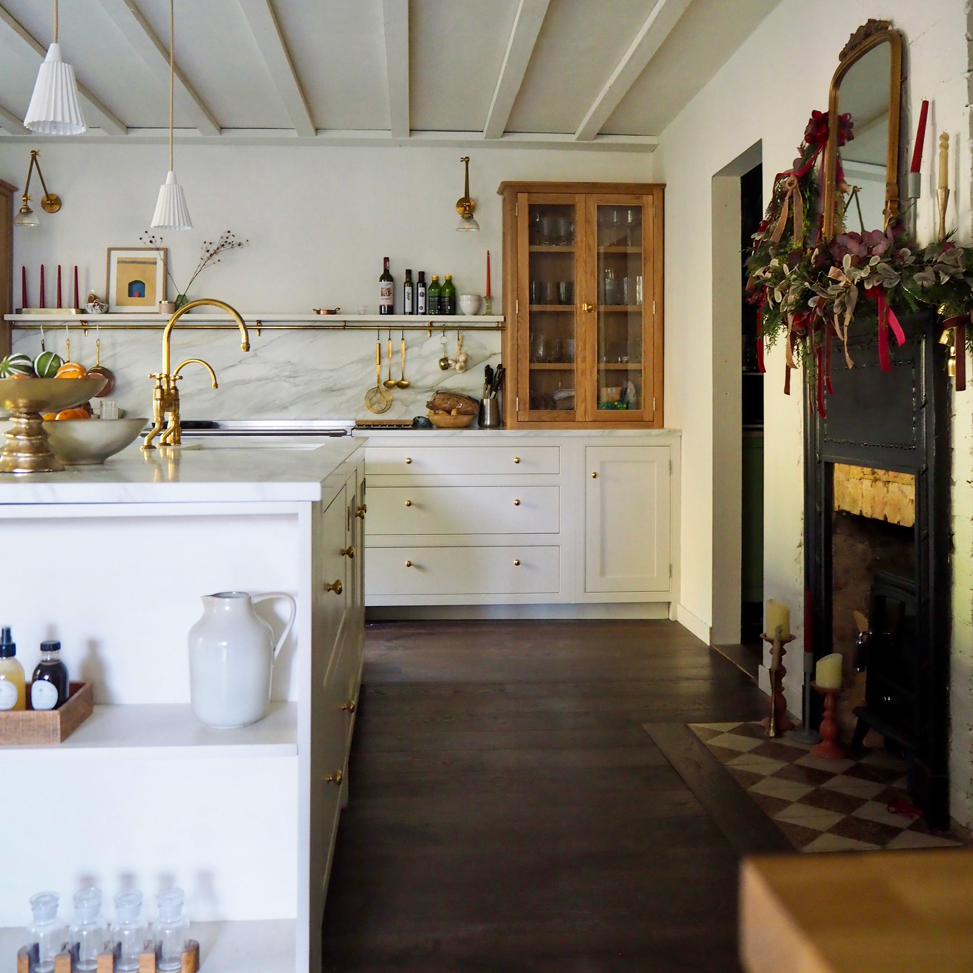 kitchen with neutral white walls and cabinetry and island with dark wood flooring and unpainted wooden unit cabinets and art deco fireplace