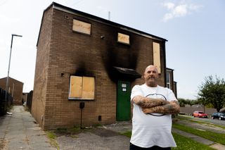 Andy Beaton in front of fire damaged house