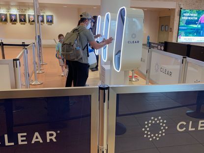 Travelers verifying their identity at CLEAR kiosks in an airport.
