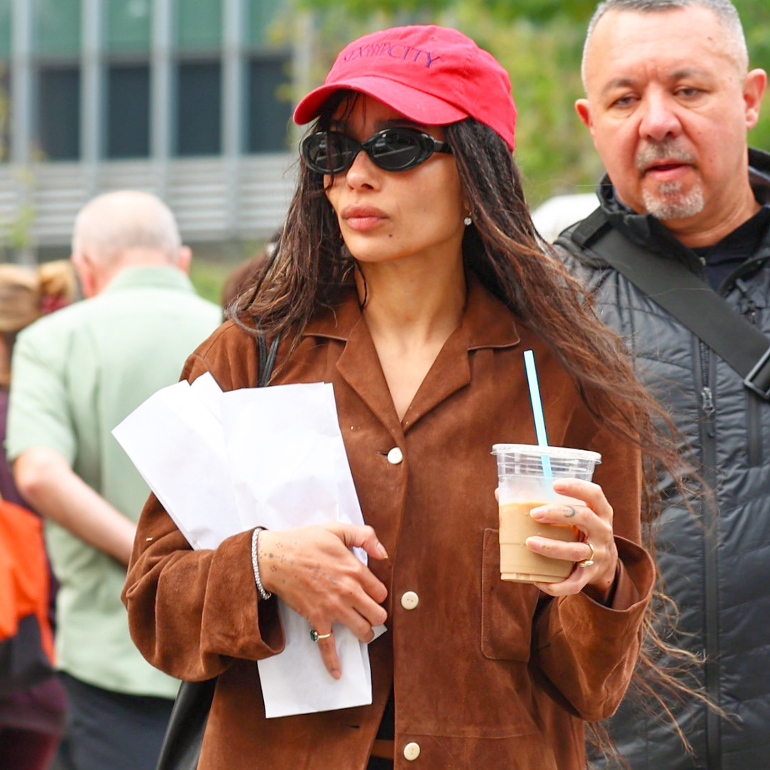 Zo&euml; Kravitz wearing a red baseball cap, brown suede jacket, micro shorts, and ballet pumps in NYC