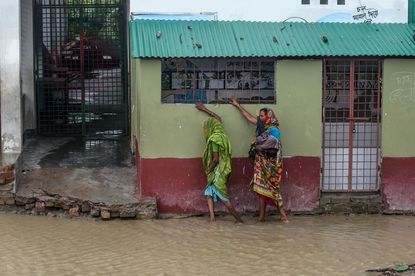 Women walk down a flooded street in Bangladesh.