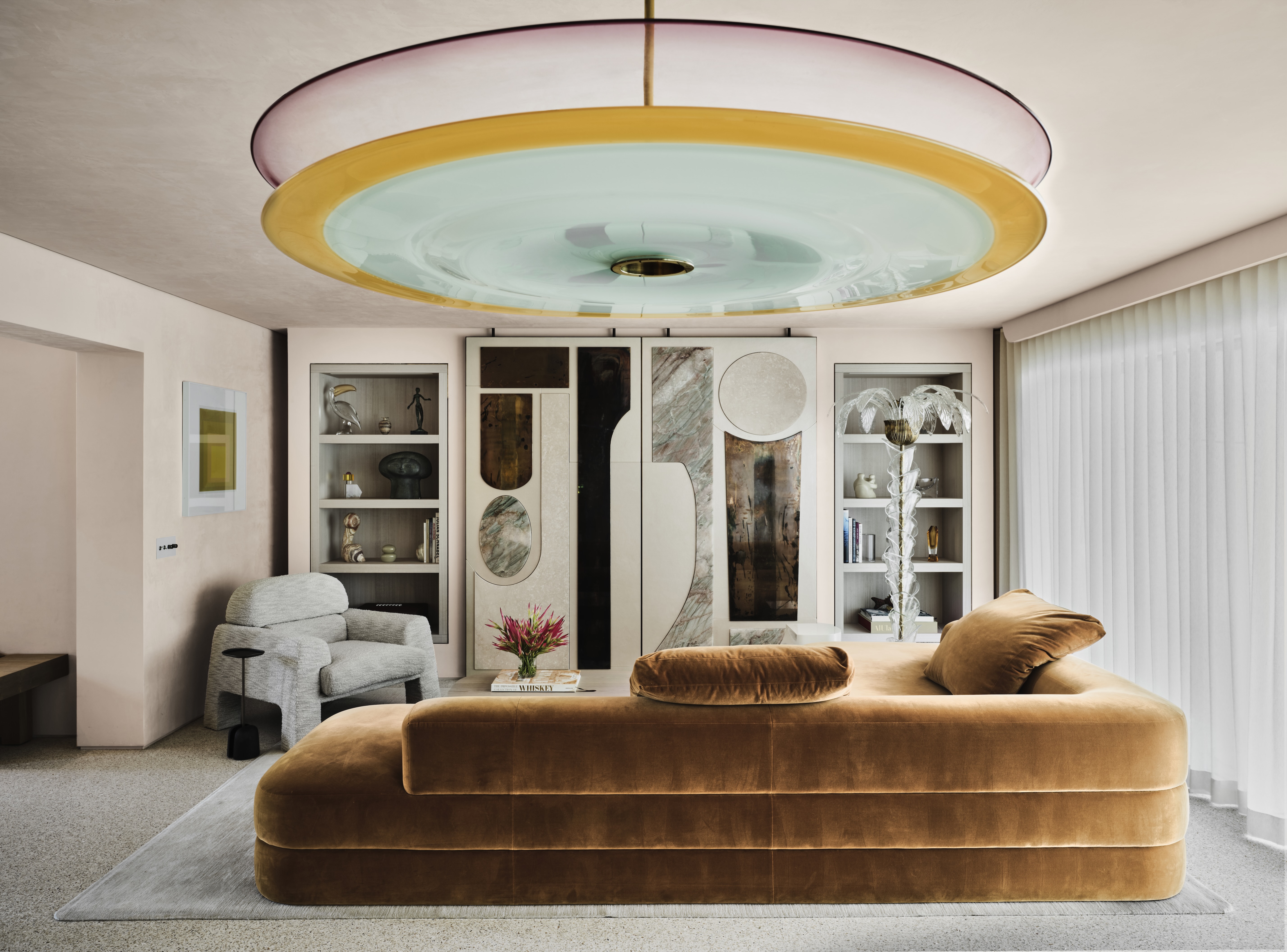 A rust-colored couch rests in a living room below a large circular light fixture.