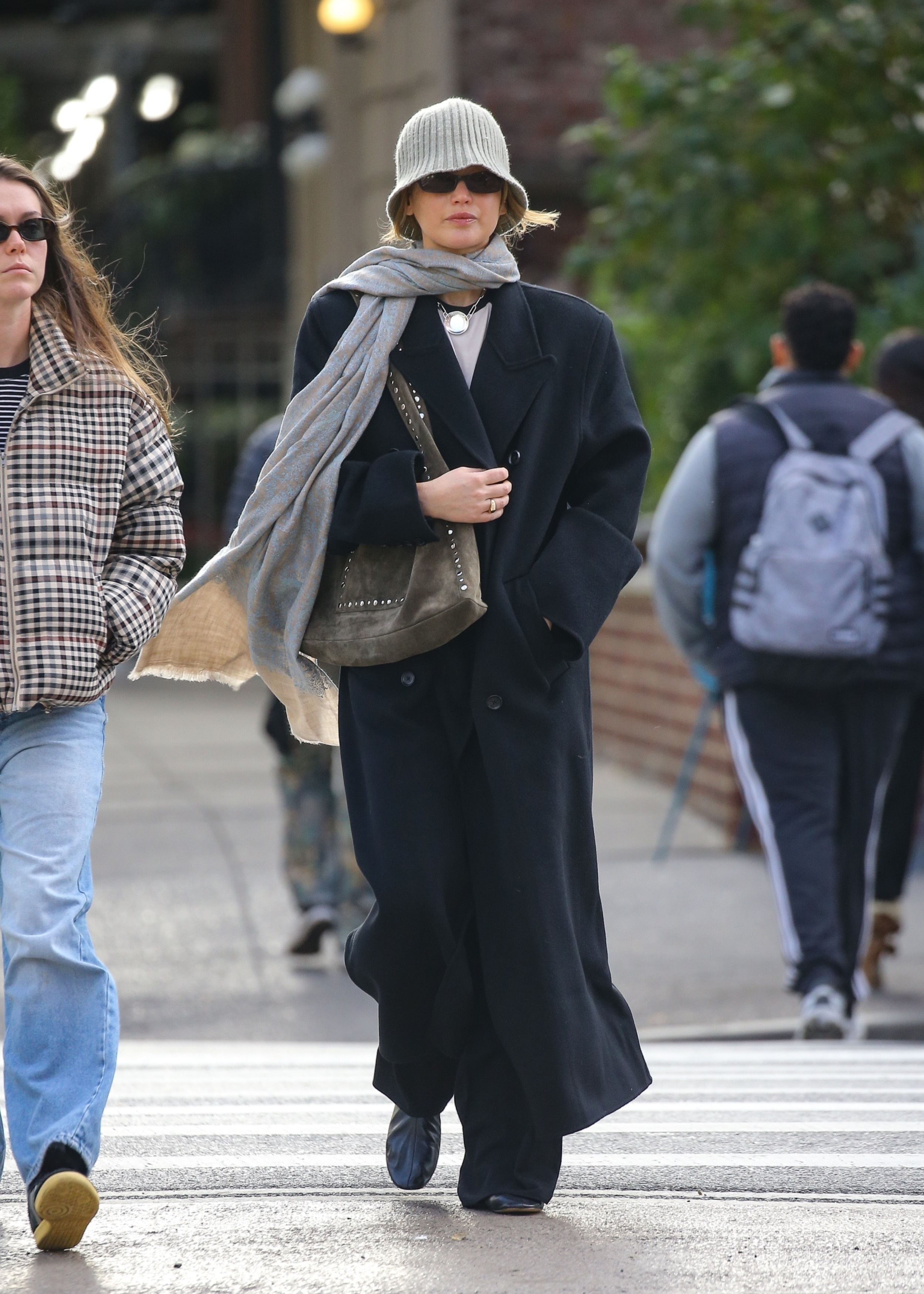 Jennifer Lawrence was spotted in NYC wearing a black wool coat, leather ballet flats, a suede bag, and a knitted bucket hat